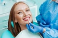 Attractive young woman with natural white teeth in dental clinic. Hands doctor dentist with teeth color palette next by face. Royalty Free Stock Photo