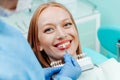 Attractive young woman with natural white teeth in dental clinic. Hands doctor dentist with teeth color palette next by face. Royalty Free Stock Photo