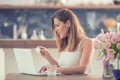 Attractive young woman online shopping using computer and credit card in home kitchen Royalty Free Stock Photo