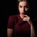 Attractive young woman with open mouth and surprised gesture, over black background. Astonishment Royalty Free Stock Photo