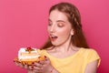 Attractive young woman with opened mouth holds plate with piece of delicious cake in hands. Brown haired lady with red manicure Royalty Free Stock Photo