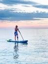 Attractive young woman paddling on SUP board on the beach. Royalty Free Stock Photo