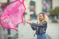 Attractive young woman with pink umbrella in the rain and strong wind. Girl with umbrella in autumn weather