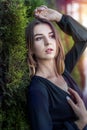 attractive young woman posing in black dress at nature, white cedar. Royalty Free Stock Photo