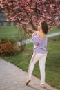 Attractive young woman in a purple sweater stand in front of sakura tree in the park Royalty Free Stock Photo