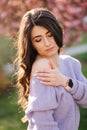 Attractive young woman in a purple sweater stand in front of sakura tree in the park Royalty Free Stock Photo