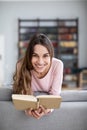 Attractive young woman is reading a book, looking at camera and smiling Royalty Free Stock Photo