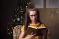 Attractive young woman reading book near christmas tree Royalty Free Stock Photo