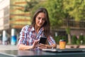 Attractive young woman reading a text message on her cell phone. Girl sitting outdoors using smartphone Royalty Free Stock Photo