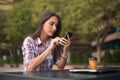 Attractive young woman reading a text message on her cell phone. Girl sitting outdoors using smartphone Royalty Free Stock Photo