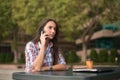 Attractive young woman reading a text message on her cell phone. Girl sitting outdoors using smartphone Royalty Free Stock Photo