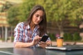 Attractive young woman reading a text message on her cell phone. Girl sitting outdoors using smartphone Royalty Free Stock Photo