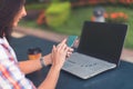 Attractive young woman reading a text message on her cell phone. Girl sitting outdoors using smartphone Royalty Free Stock Photo