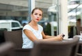 Attractive young woman reads a newspaper sitting in a cafe