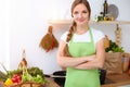 An attractive young woman ready to cook a new recipe for a delicious salad mix while standing in sunny kitchen