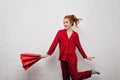 Attractive young woman in red cotton pajamas dancing with paper bag. Indoor portrait of happy blonde girl posing with Royalty Free Stock Photo