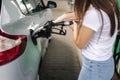 Attractive young woman refueling car at gas station. Female filling diesel at gasoline fuel in car using a fuel nozzle Royalty Free Stock Photo