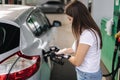 Attractive young woman refueling car at gas station. Female filling diesel at gasoline fuel in car using a fuel nozzle Royalty Free Stock Photo