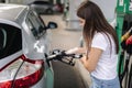 Attractive young woman refueling car at gas station. Female filling diesel at gasoline fuel in car using a fuel nozzle Royalty Free Stock Photo