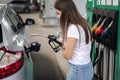 Attractive young woman refueling car at gas station. Female filling diesel at gasoline fuel in car using a fuel nozzle Royalty Free Stock Photo