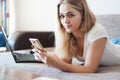 Attractive young woman relaxing on a sofa at home and using smart phone Royalty Free Stock Photo