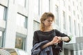 Attractive young woman in a rush looking at the watch on her wrist checking time. Cute girl waiting for a partner to go on the Royalty Free Stock Photo