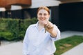 Attractive young woman showing key while standing outdoor against new house. Real estate agent holding key on street Royalty Free Stock Photo