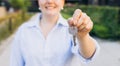 Attractive young woman showing key while standing outdoor against new house. Real estate agent holding key on street Royalty Free Stock Photo