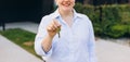 Attractive young woman showing key while standing outdoor against new house. Real estate agent holding key on street Royalty Free Stock Photo