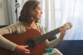 Attractive young woman sitting at home playing the Spanish guitar Royalty Free Stock Photo