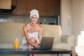 Attractive young woman sitting at the kitchen table, working on laptop computer Royalty Free Stock Photo