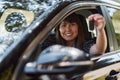 Attractive young woman sitting in new car and holding out new keys. Royalty Free Stock Photo