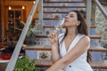 Attractive young woman is sitting on terrace steps of house and drinking champagne Royalty Free Stock Photo