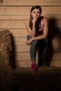 Attractive young woman in sporty dress in a barn posing with hay Royalty Free Stock Photo