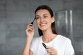 Attractive young woman applying black brown mascara on lashes. Royalty Free Stock Photo