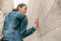 Attractive young woman stands between concrete walls. Caucasian girl in casual jeans and dress looks back Royalty Free Stock Photo