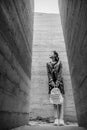 Attractive young woman stands between concrete walls. Caucasian girl in casual jeans and flower dress looks up. Royalty Free Stock Photo