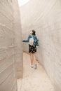 Attractive young woman stands between concrete walls. Caucasian girl in casual jeans looks up. Royalty Free Stock Photo