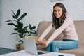 attractive young woman stretching hands and smiling at camera while using laptop Royalty Free Stock Photo