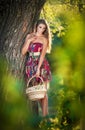 Attractive young woman in a summer fashion shot. Beautiful fashionable young girl with straw basket in park near a tree Royalty Free Stock Photo