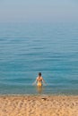 Attractive young woman in swimsuit stands waist-deep in the calm morning sea water Royalty Free Stock Photo