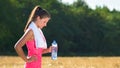 Attractive young woman taking a break after jogging, holding bottle of water