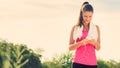 Attractive young woman taking a break after jogging, holding smartphone