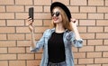 Attractive young woman taking selfie picture by smartphone wearing a black round hat over background Royalty Free Stock Photo