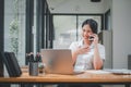 Attractive young woman talking on the mobile phone and smiling while sitting at her working place in office Royalty Free Stock Photo