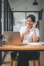 Attractive young woman talking on the mobile phone and smiling while sitting at her working place in office Royalty Free Stock Photo