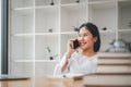 Attractive young woman talking on the mobile phone and smiling while sitting at her working place in office Royalty Free Stock Photo