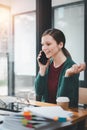 Attractive young woman talking on the mobile phone and smiling while sitting at her working place in office Royalty Free Stock Photo