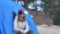 Attractive young woman tourist in a red hat sits in a tourist tent and enjoys a virtual reality helmet
