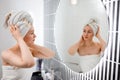 Attractive young woman in towel is looking at mirror standing in bathroom after taking shower. Beauty and Skincare concept Royalty Free Stock Photo